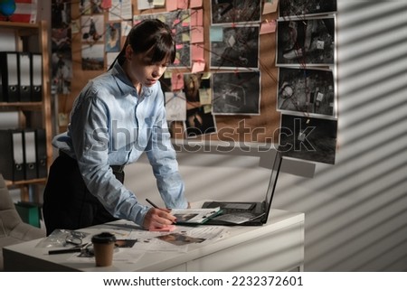 Detective working at desk with laptop computer in her office. Copy space