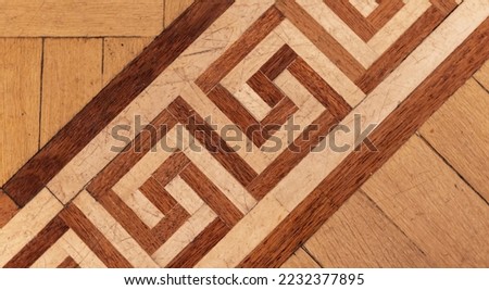 Vintage parquet made of of various wood planks with geometric ornament known as the Greek Key or Meander. Background photo texture, top view