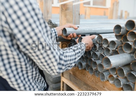 closup of male hand gripping metal tube in industrial factory.