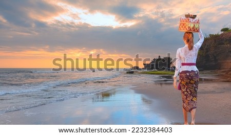 Balinese women carrying on religious offering - Tanah Lot Temple at sunset - Most important hindu temple - Bali, Indonesia