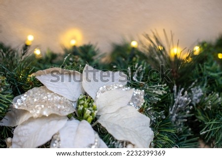 view from above of christmas ornament in shape of white flower with glitter on background of lights