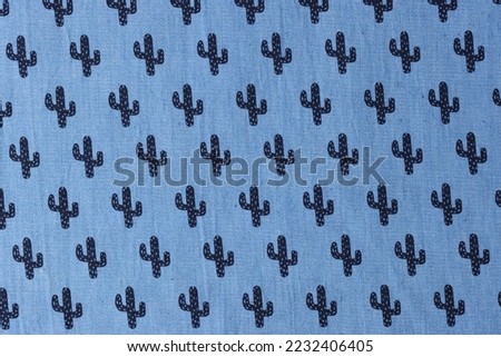 Bright and dark blue textile with cactus ornament as background. Close up of fabric with cactus picture.