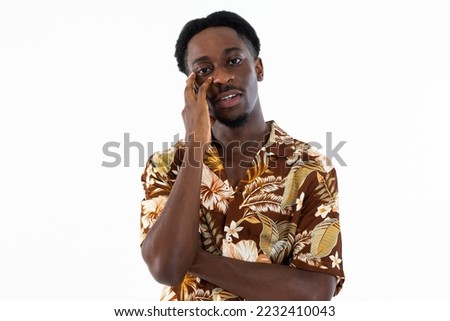 Curious delighted handsome man holding arms near face looking at camera talking crossed arms in chest wearing colorful shirt standing on white background in studio.