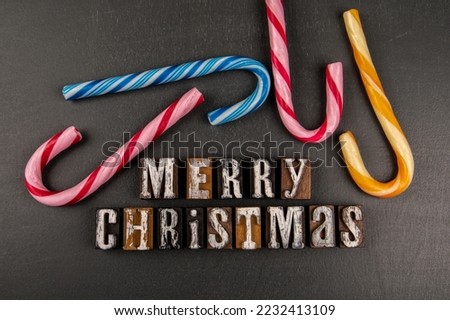 MERRY CHRISTMAS. Text and colorful candies on blackboard background.
