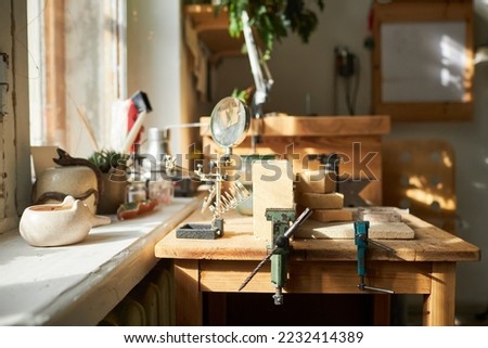 Background image of jewelers workstation with wooden table lit by sunlight in studio, copy space Royalty-Free Stock Photo #2232414389