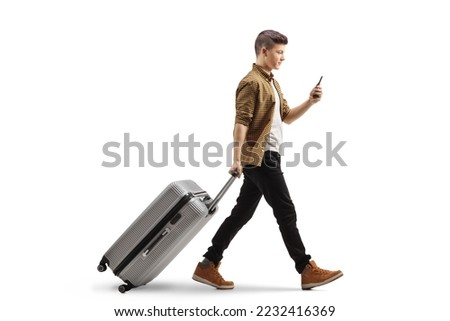 Full length profile shot of a guy with a smartphone pulling a suitcase isolated on white background

 Royalty-Free Stock Photo #2232416369