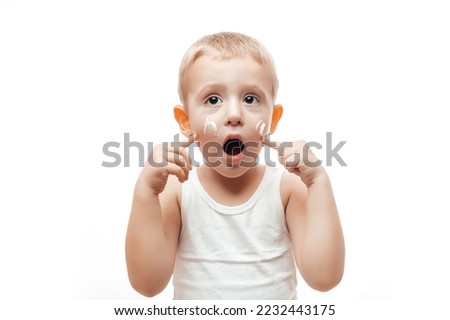 Portrait of cute little caucasian boy applying winter cream for protect skin on white background. concept cleaning wipe, pure, clean.