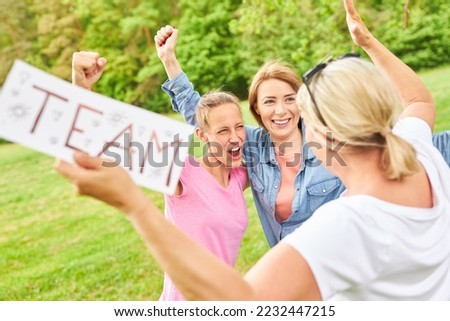 Group of women cheering a success in outdoor competition with team sign in hands