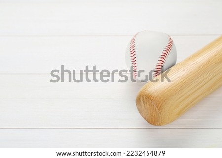 Baseball bat and ball on white wooden table, above view with space for text. Sports equipment