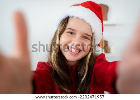 Little girl with big smile looking at the camera and celebrating christmas with family,Cheerful family with santa hats,Merry Christmas and Happy Holidays.