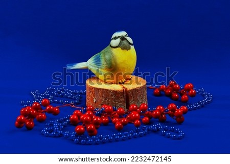 A Christmas card with a yellow bird.  Christmas tree beads.He's sitting on a tree stump. A branch of red berries, mountain ash, cranberries.The concept of Christmas. New Year's scene.  space for text.