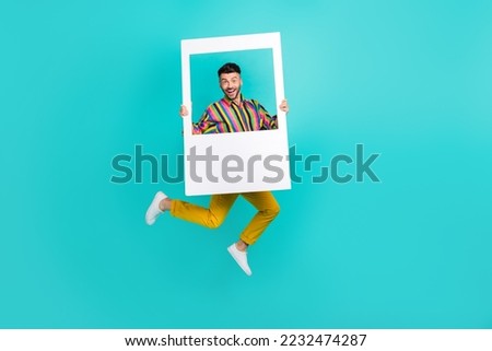 Full body length photo of funky jumping air trampoline man wear retro old fashion clothes hold paper frame cadre event isolated on blue background