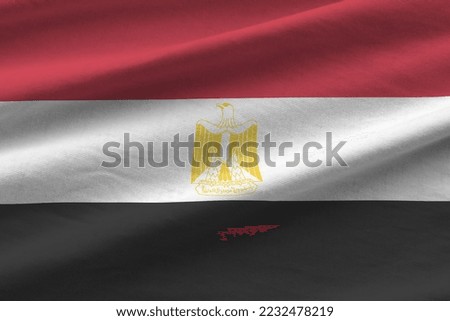 Egypt flag with big folds waving close up under the studio light indoors. The official symbols and colors in fabric banner