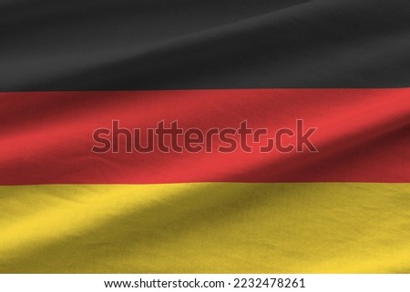 Germany flag with big folds waving close up under the studio light indoors. The official symbols and colors in fabric banner