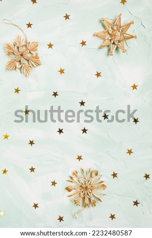 Christmas straw decoration snowflakes and golden foil stars on green and white backround. Winter holidays concept. Flat lay, copy space, top view