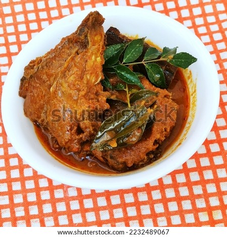 Fish curry dish in white bowl laid on plaid table cloth 