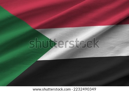 Sudan flag with big folds waving close up under the studio light indoors. The official symbols and colors in fabric banner Royalty-Free Stock Photo #2232490349