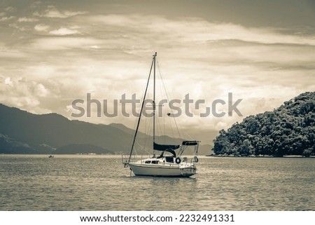 Old black and white picture of Boats ships and Boat trips from Abraao beach Ilha Grande Angra dos Reis Rio de Janeiro Brazil.