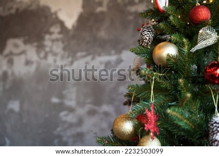 Christmas border branches of fir tree with decoration and grey concrete wall. Background with copy space and Christmas tree details