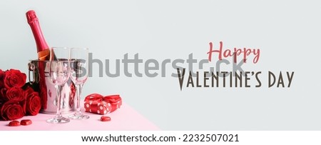 Valentine's day greeting card with gift, red roses, and sparkling wine in bucket on pastel blue background. Banner. Greeting card with text - Happy Valentine's day.