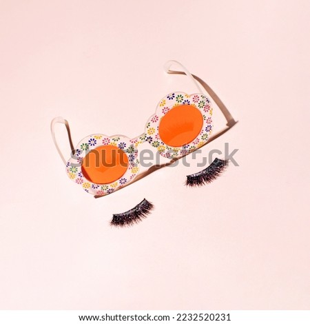 Cute sunglasses for girls and false eyelashes, creative aesthetic retro style layout against pale pink background. 