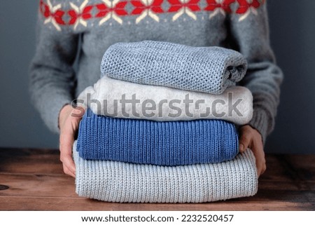 Female hands making up on a stack on a wooden table. Change of season and wardrobe. Used clothes. Sustainable clothing and responsible consumption concept. High quality photo