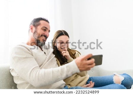 A father with teen child daughter having fun using cellphone at home