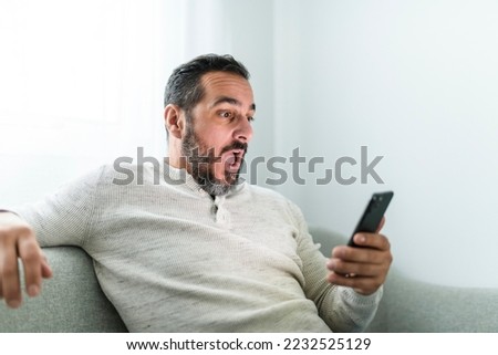 A man with smartphone sit on sofa at home