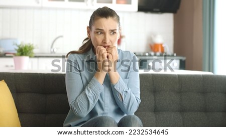 Nervous woman feeling panic, biting her nails, feeling anxious and confused. Frustrated and stressed woman waiting for someone at home. Angry woman biting her nails. Feelings of anxiety, fear. Royalty-Free Stock Photo #2232534645