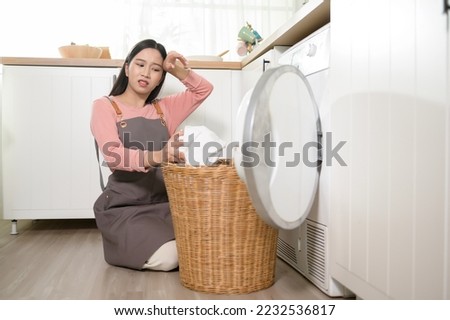 Exhausted  Asian young woman with dirty clothes , doing laundry in home  Royalty-Free Stock Photo #2232536817