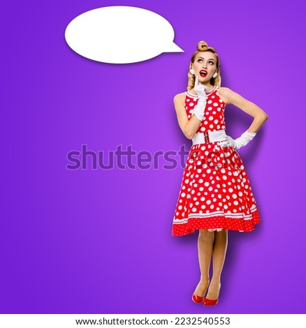 Full body length image of thinking woman in red pin up dress. Blond pinup thougthfull girl in studio, on violet background. White empty blank speech sign bubble, having idea.