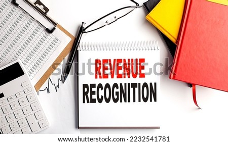 REVENUE RECOGNITION text on notebook with clipboard and calculator on a white background