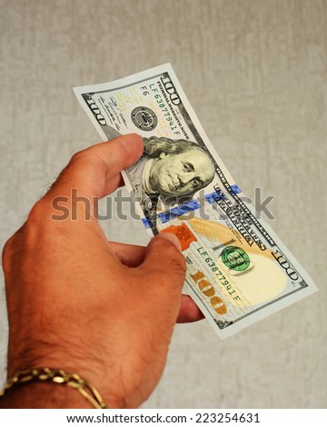 A $100 bill in a man's hand. A very valuable banknote that lifts your spirits. American cash is popular all over the world. Well-known currency. 100 dollar bill in a man's hand. Stock photo. 