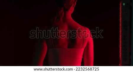 Woman getting red light therapy on her back. Rearview of a woman standing next to a red light device in a beauty salon. Anti-aging cosmetic treatment. Royalty-Free Stock Photo #2232568725