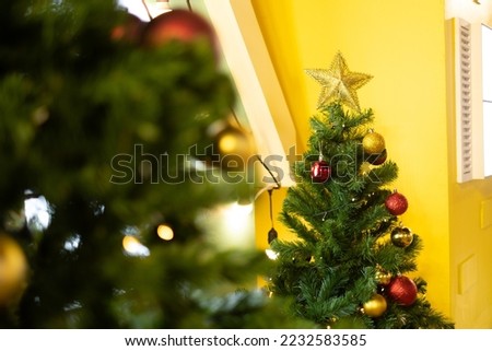green Christmas tree with blurry foreground of Christmas tree and with yellow background