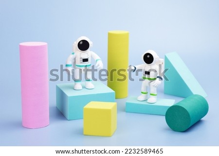 Plastic figurines of an astronauts in a spacesuit and geometric shapes on a blue background. Children's toys astronauts. Fascination with space, the study of planets.