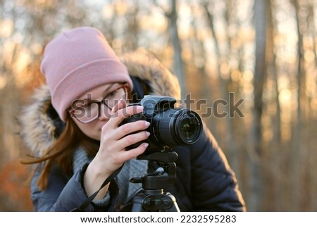 A young woman with a camera takes pictures of nature