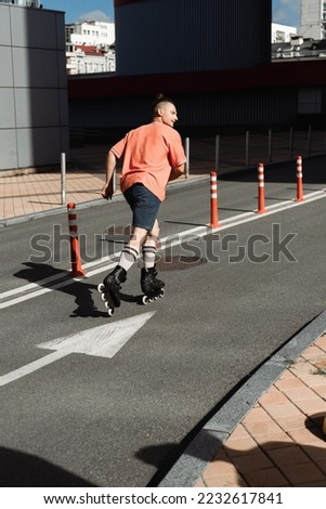 Side view of man in roller skates skating on road on urban street