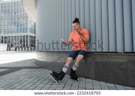 Smiling man in roller skates having video call on urban street