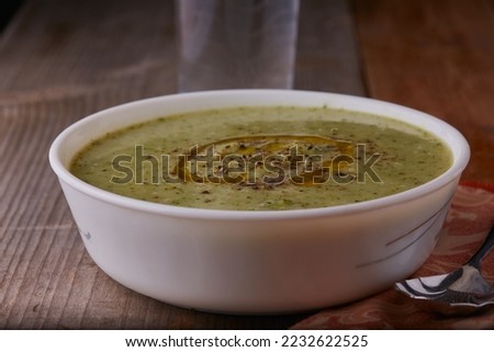 Bowl of broccoli soup garnished with cheese and pepper with a splash of olive oil.