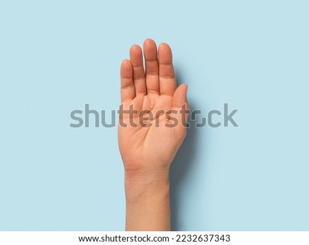 Empty hand palm of caucasian woman over pastel blue background. Open hand gesture close-up. Adult female person right hand macro. Body parts concept. Directly above view.