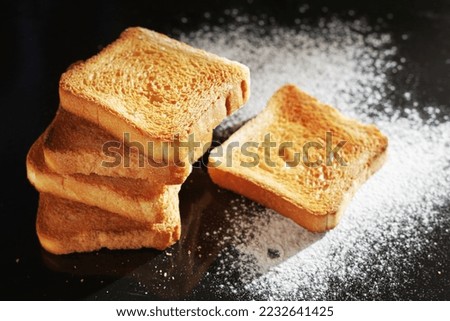Slices of small toasted bread on black metal tray with flour 