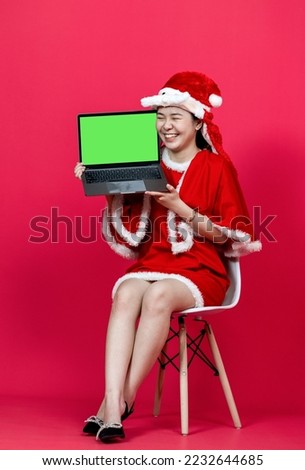 Green screen mockup of a laptop held by a woman wearing red christmas attire on a red background