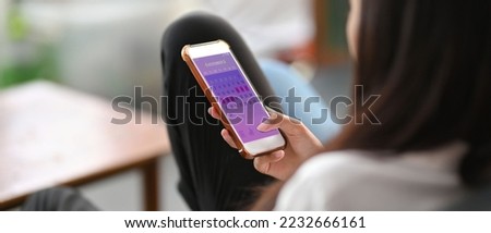 Mobile application for monitoring the menstrual cycle on the smartphone screen in the hands of the woman. The woman is sitting on the sofa with the mobile. Royalty-Free Stock Photo #2232666161