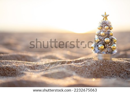 Golden hour sunset on the beach of small Christmas tree in silver and gold,  Christmas banner, Christmas banner, happy concept, copy space, soft focus