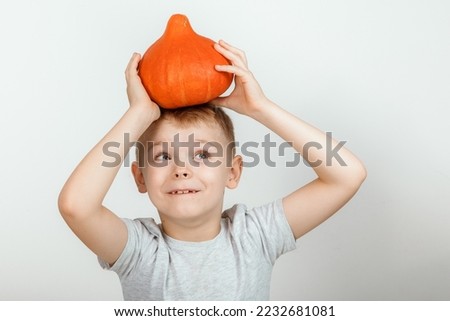 Boy with a pumpkin on a white background. Smiling kid with a pumpkin, Halloween holiday concept. Cute little boy with pumpkin.