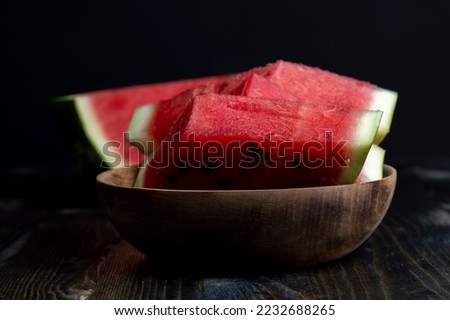 Sliced red and ripe watermelon on the table, juicy pieces of watermelon sliced on a black board
