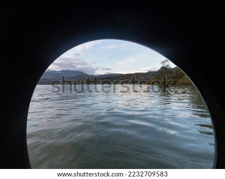 Beautiful andean lake and mountain landscape sunset viewed through an ancient wheel 