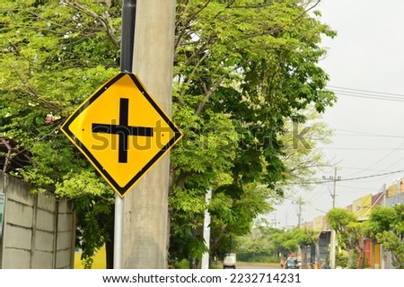 Yellow road junction traffic sign on roadside in industrial and warehouse complex