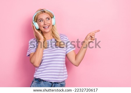 Photo of mature age woman wear striped purple t-shirt finger point empty space recommend new soundtrack isolated on pink color background